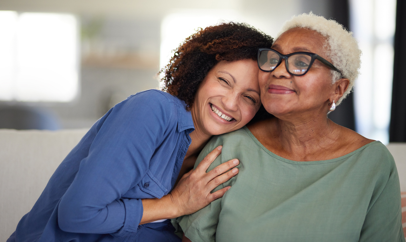 A heartwarming image of a smiling younger woman embracing her content older mother. Both women exude joy and affection in a close, intimate moment, bathed in soft, natural light.